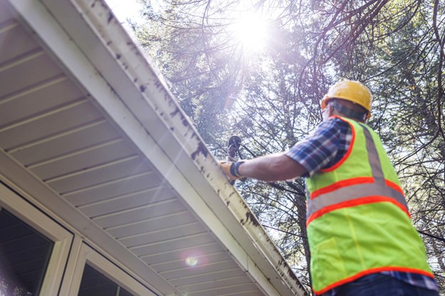 A person in a yellow safety vest and hard hat inspecting a roof in Logan, Utah