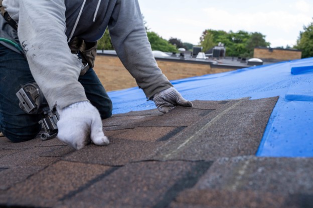 A person installing asphalt shingles in Logan, Utah