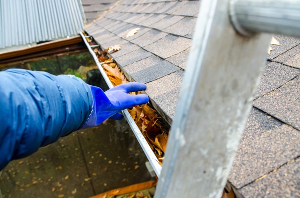A Skabelund Roofing professional cleaning the roof gutter of a house in Cottonwood Heights, UT