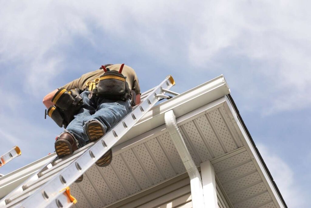 A professional inspecting the roof gutter of a house in Logan & Layton, UT