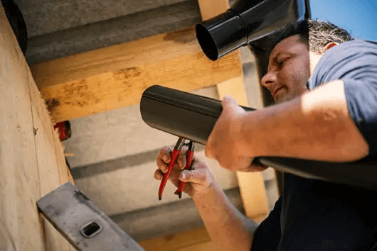 A technician is performing Gutter Repair Services at a residential home in Logan, UT 